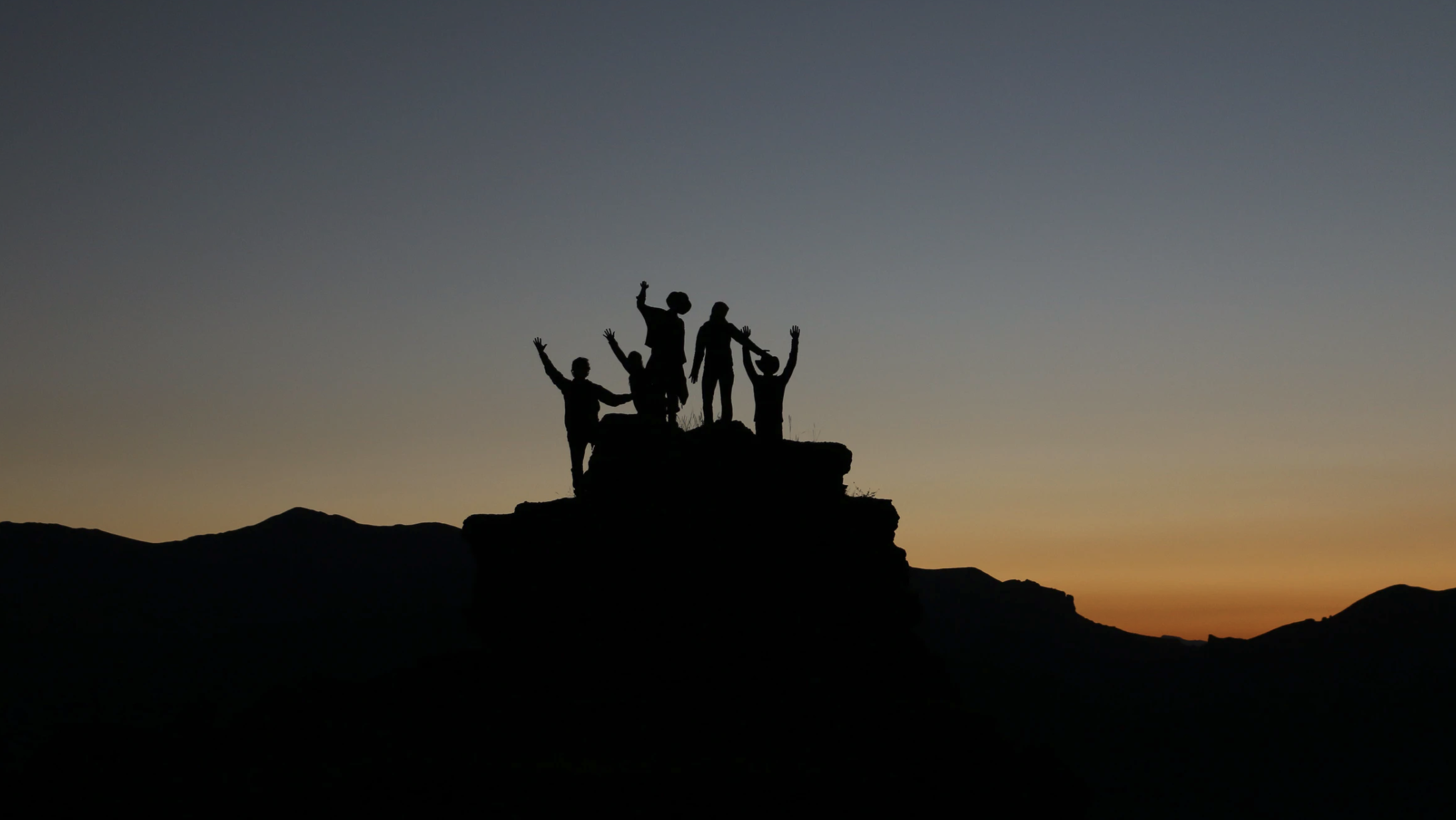 sunset photo of a mountain with a small group of people in silhouette
